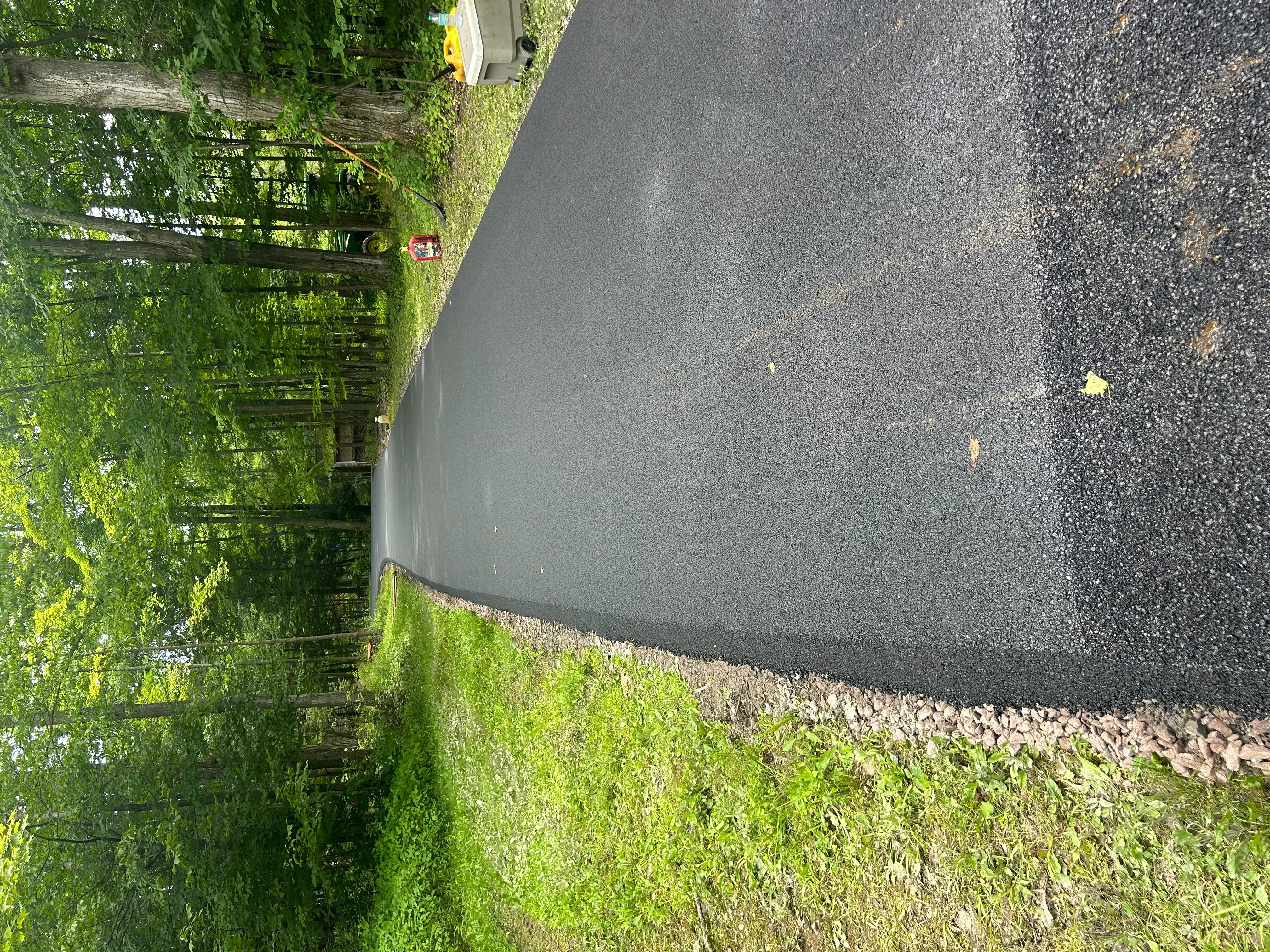 New asphalt driveway with dark surface and gravel base edge