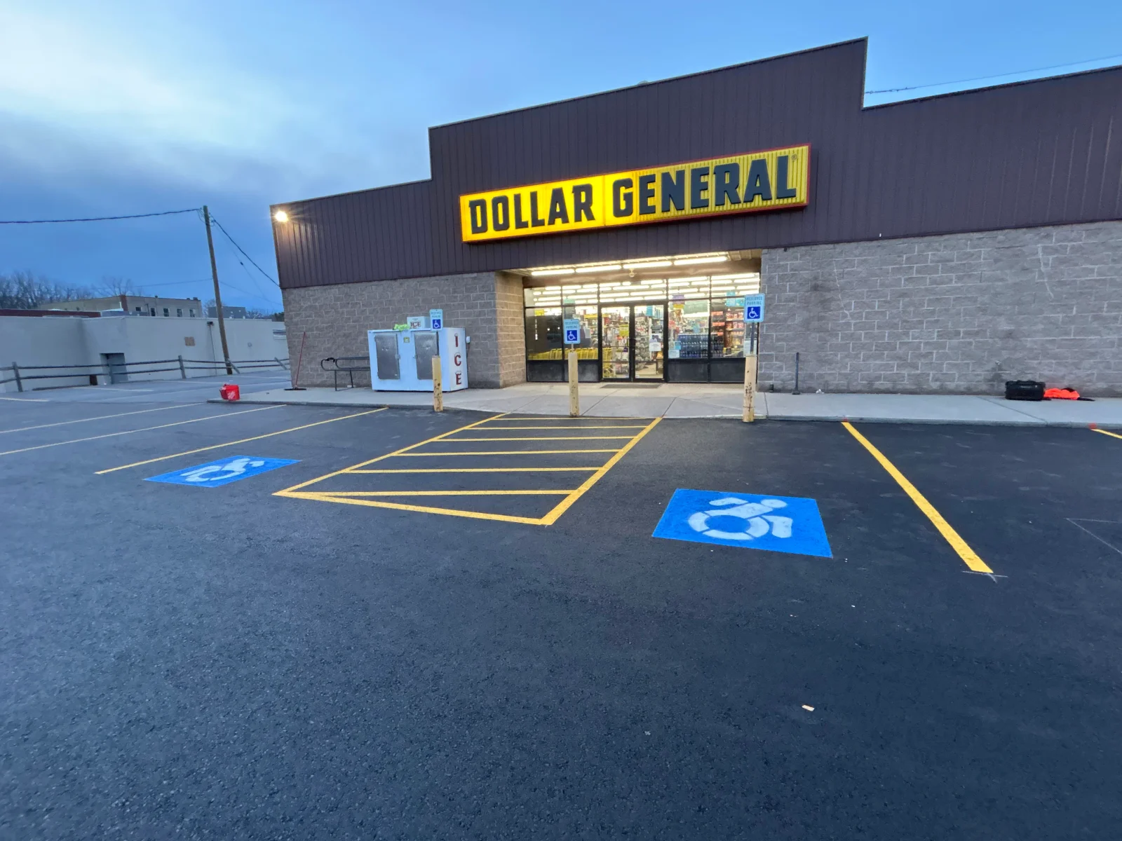 Asphalt parking lot with yellow striping, ADA accessible parking spaces marked in blue, retail storefront entrance