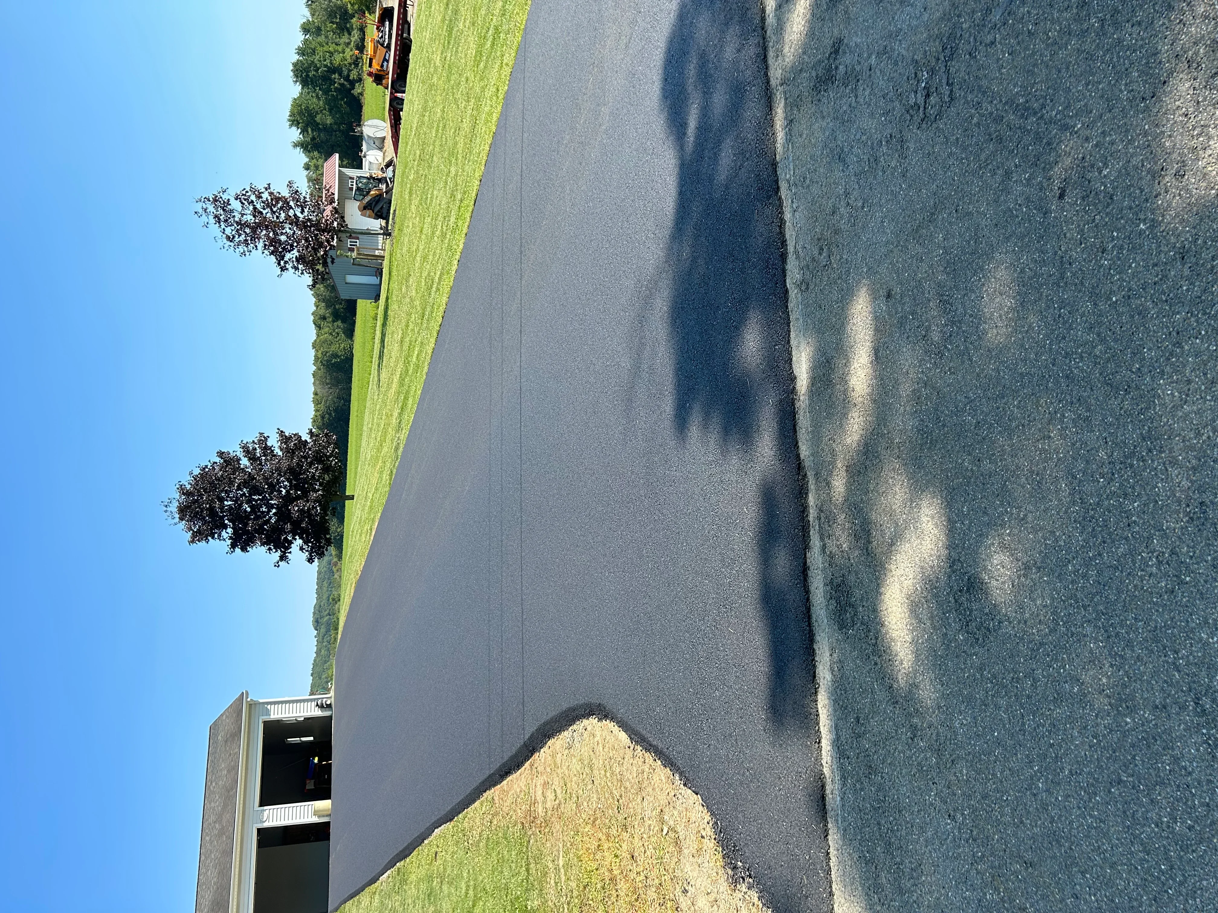 Newly paved asphalt driveway with clean edges and manicured lawn borders