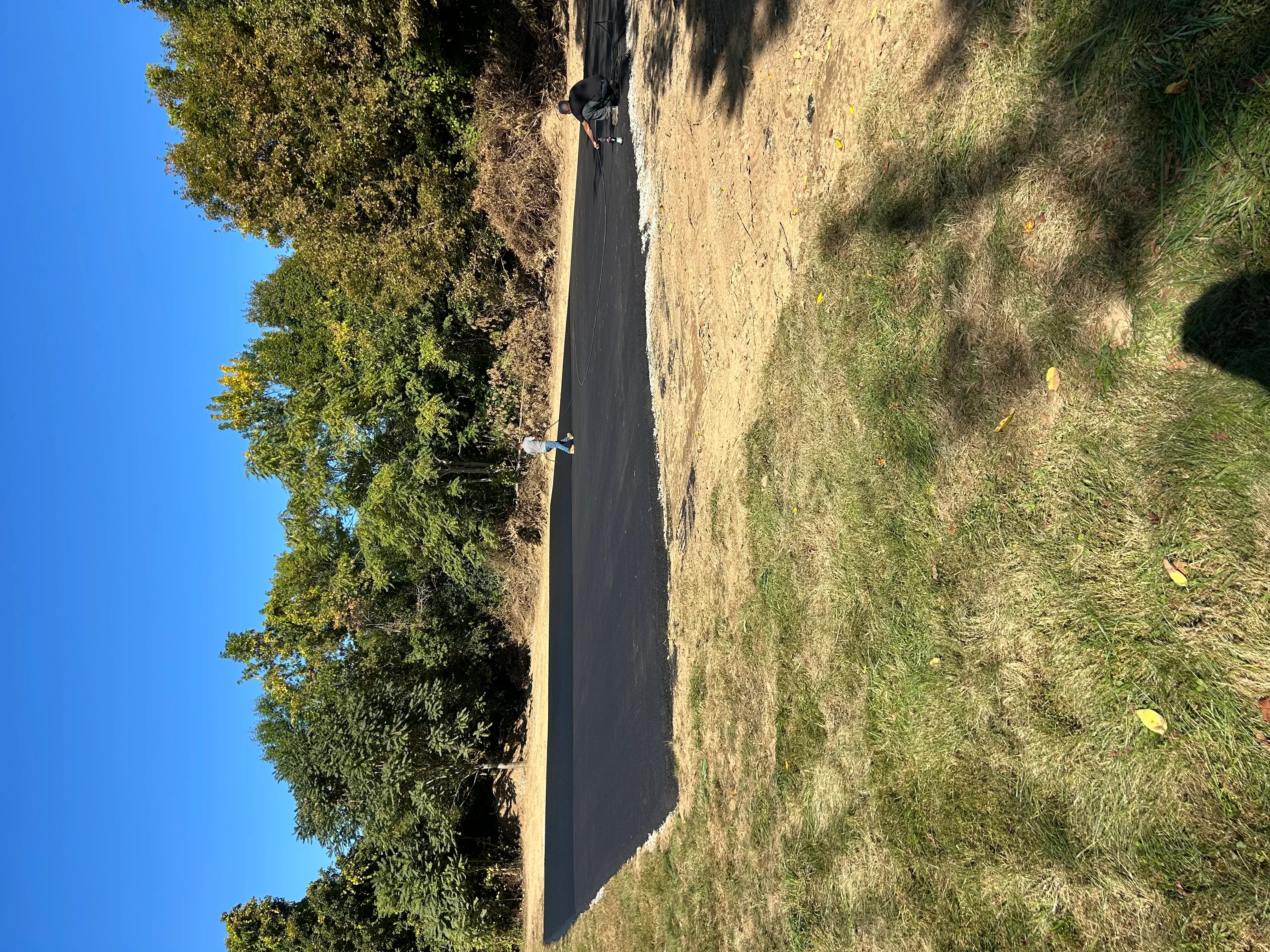 Newly installed black asphalt driveway with compacted surface and proper grading