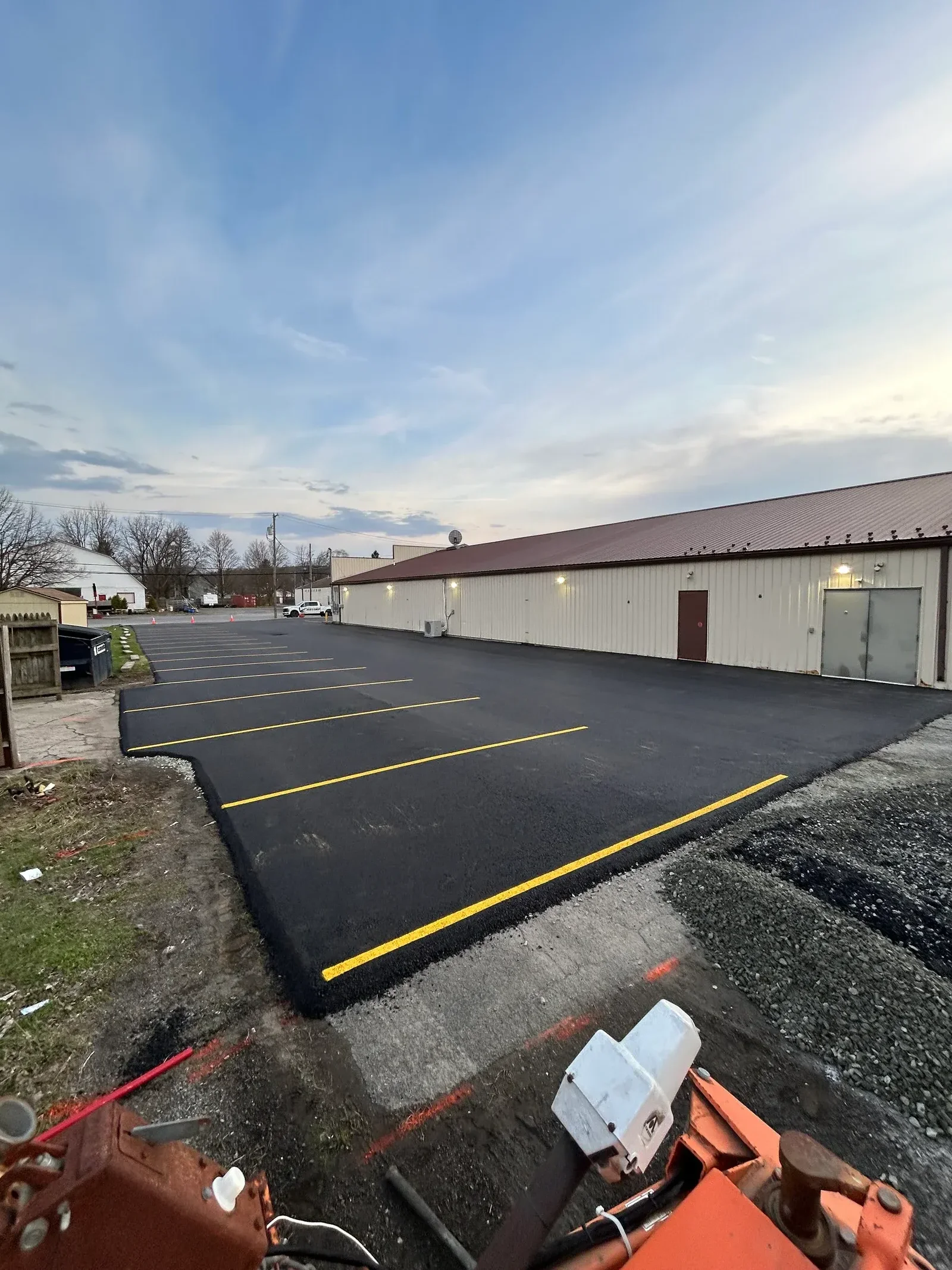 Newly paved asphalt parking lot with yellow center line markings and striping layout