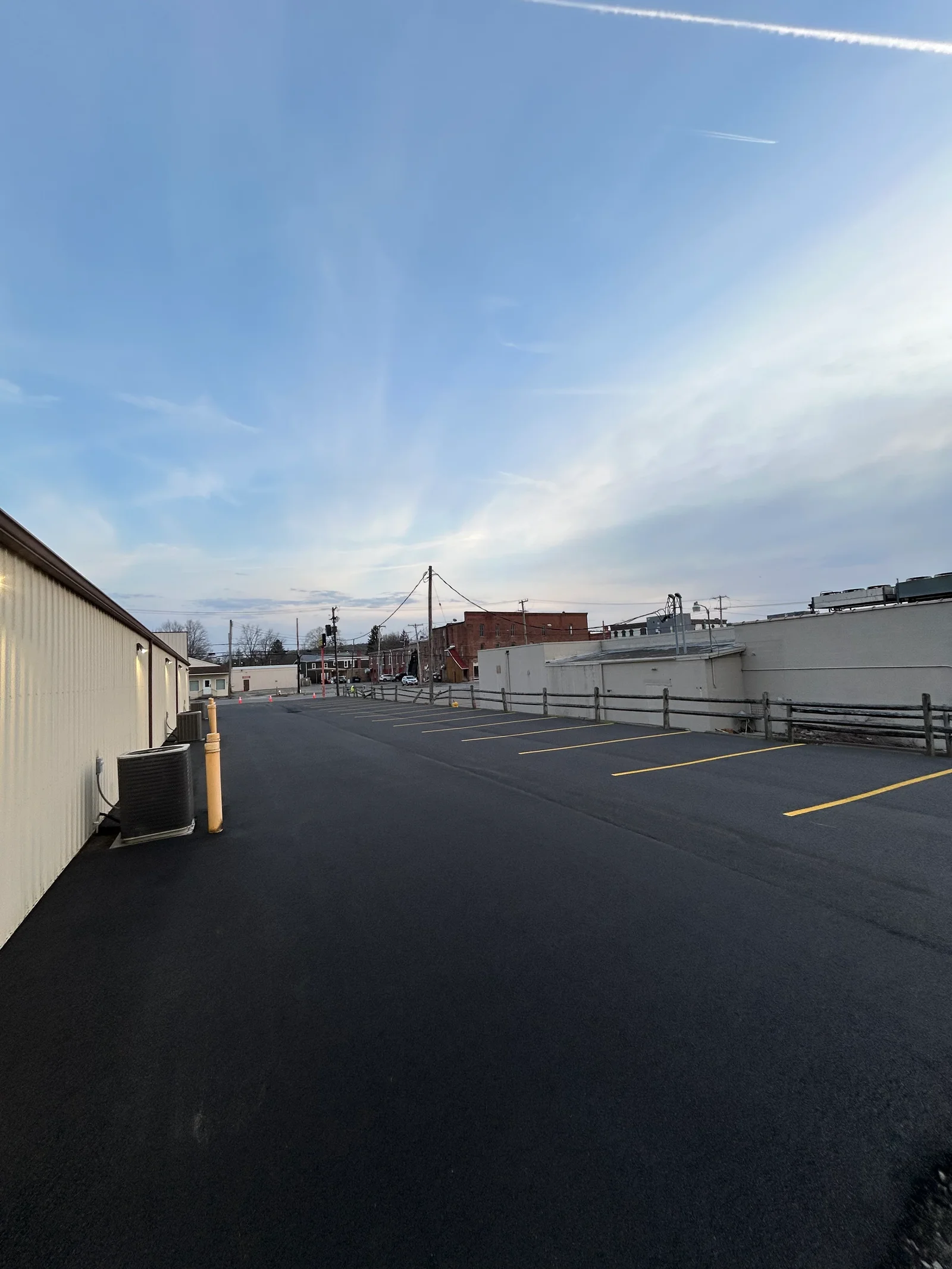 Fresh black asphalt paving with yellow center line markings and drainage systems