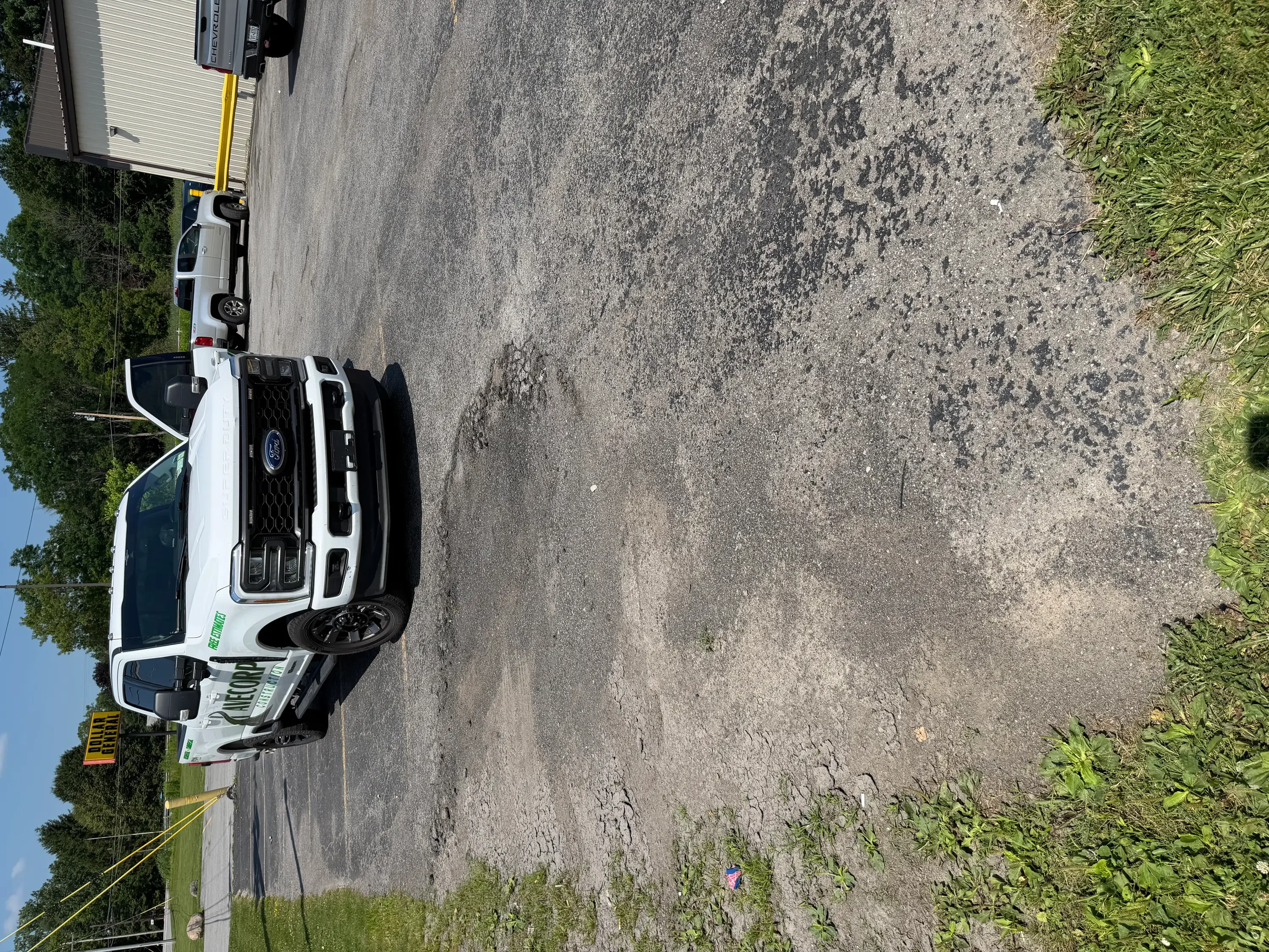 White pickup truck on newly paved asphalt driveway with fresh black asphalt surface